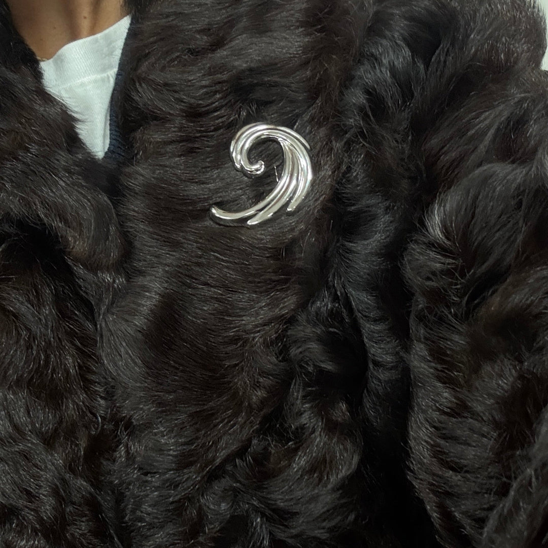 Black fur coat with a silver brooch on a neutral background